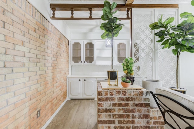 interior space featuring hardwood / wood-style floors, beam ceiling, and brick wall