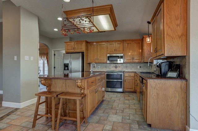 kitchen with stainless steel appliances, a center island, sink, and a kitchen bar