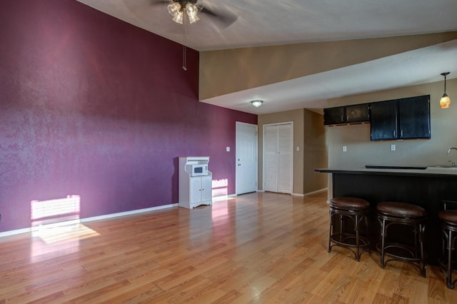 kitchen featuring vaulted ceiling, a breakfast bar, sink, ceiling fan, and light hardwood / wood-style floors