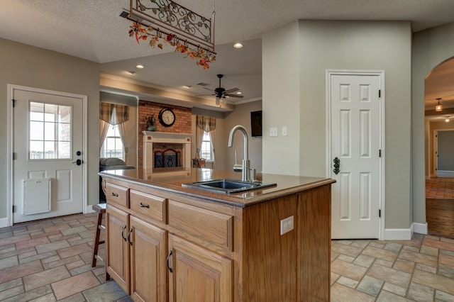 kitchen featuring sink, a kitchen bar, a kitchen island with sink, ceiling fan, and a textured ceiling