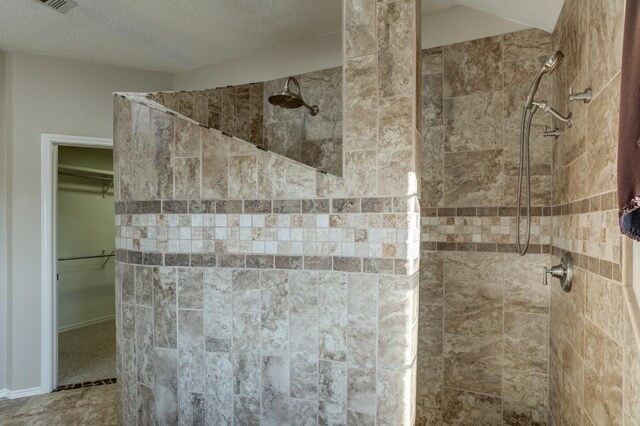 bathroom with tiled shower and a textured ceiling