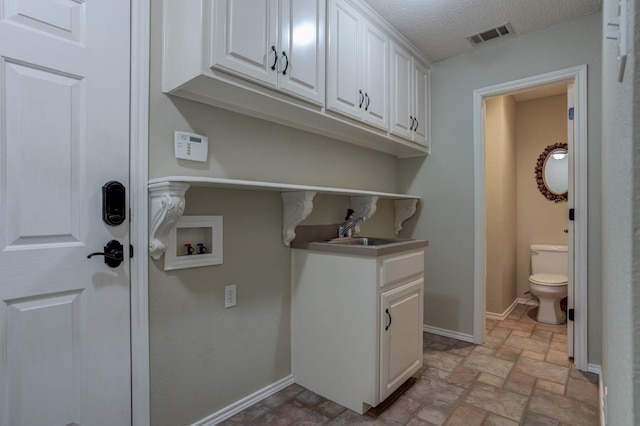 laundry area featuring cabinets, washer hookup, sink, and a textured ceiling