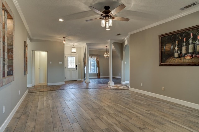 unfurnished living room with ceiling fan, ornamental molding, wood-type flooring, and a textured ceiling