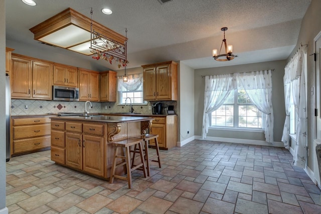 kitchen featuring a breakfast bar, a center island with sink, a chandelier, and decorative light fixtures