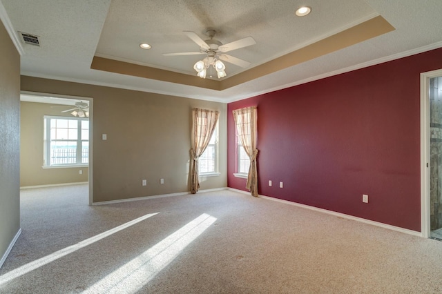 carpeted spare room featuring ceiling fan, ornamental molding, a raised ceiling, and a textured ceiling