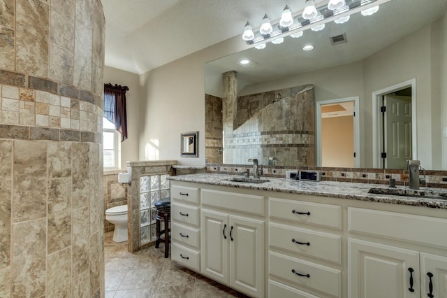 bathroom featuring tile walls, tile patterned flooring, tiled shower, vanity, and toilet