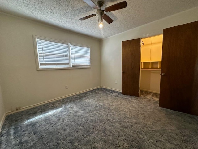 unfurnished bedroom featuring dark colored carpet, a spacious closet, a textured ceiling, and a closet