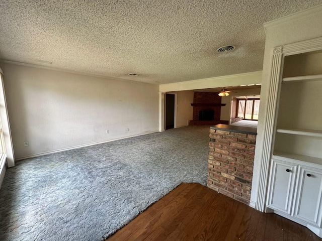 unfurnished living room featuring ceiling fan, crown molding, a textured ceiling, and a fireplace