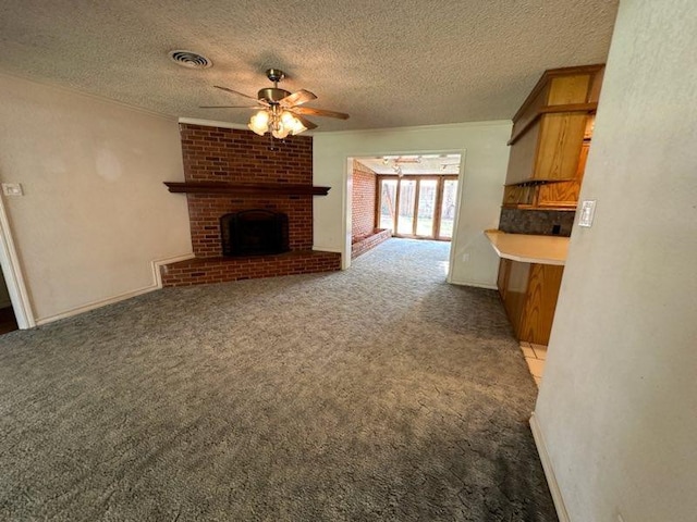 unfurnished living room with a brick fireplace, dark carpet, a textured ceiling, and ceiling fan