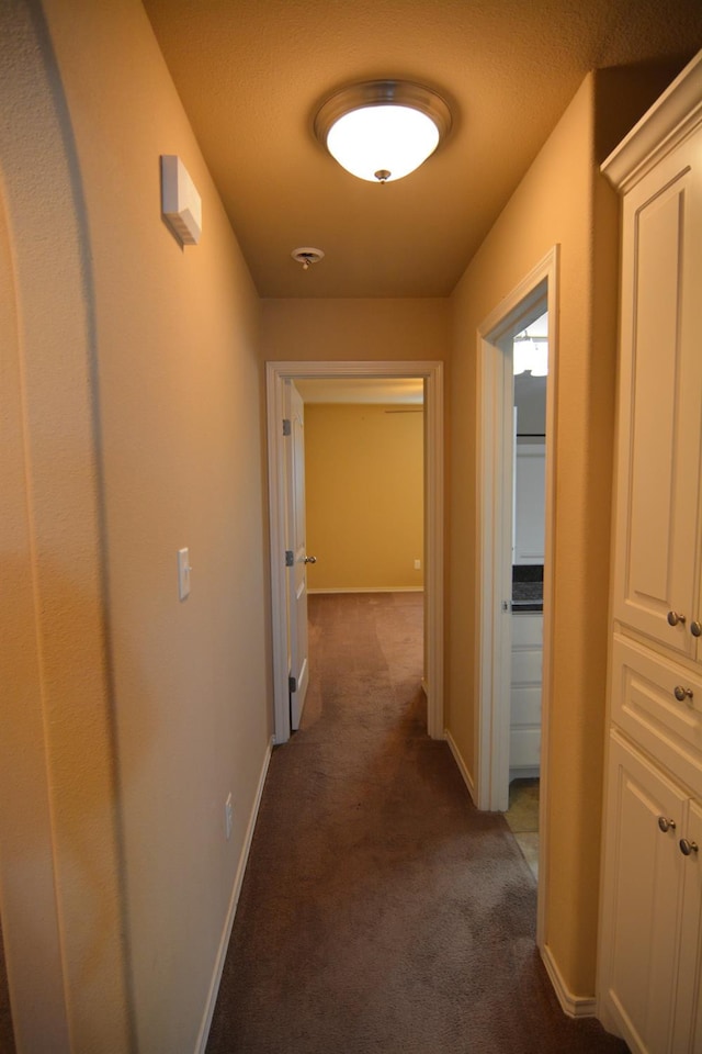 hallway featuring dark colored carpet