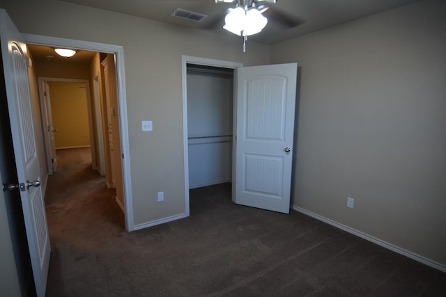 unfurnished bedroom with dark colored carpet and a closet