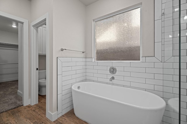 bathroom with wood-type flooring, toilet, a bathing tub, and tile walls