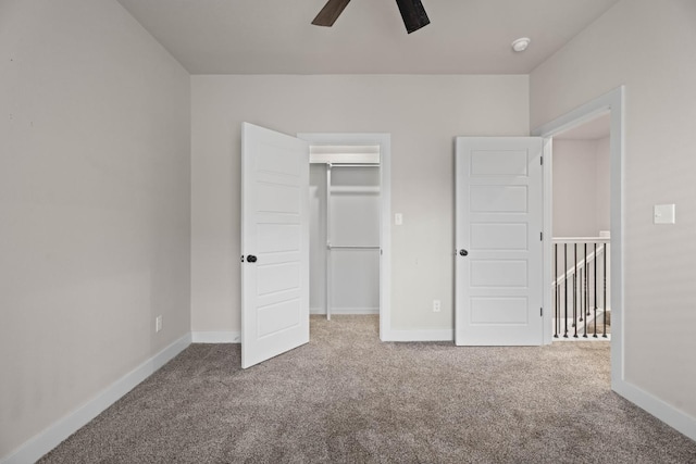 unfurnished bedroom featuring ceiling fan, a closet, a spacious closet, and carpet