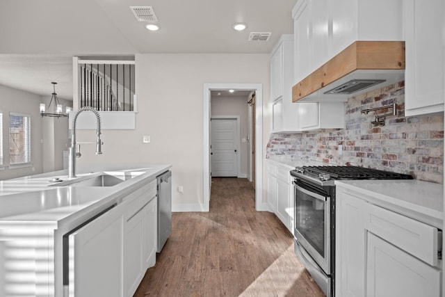 kitchen featuring premium range hood, decorative light fixtures, tasteful backsplash, white cabinets, and stainless steel appliances