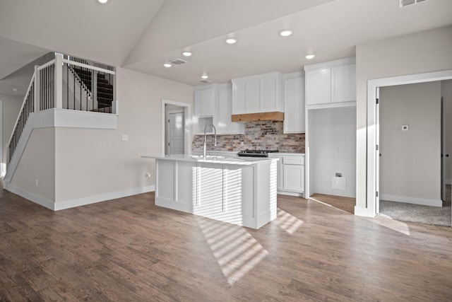 kitchen with hardwood / wood-style floors, tasteful backsplash, lofted ceiling, white cabinets, and a kitchen island with sink