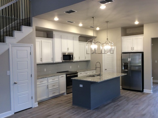 kitchen with white cabinetry, appliances with stainless steel finishes, sink, and a center island with sink