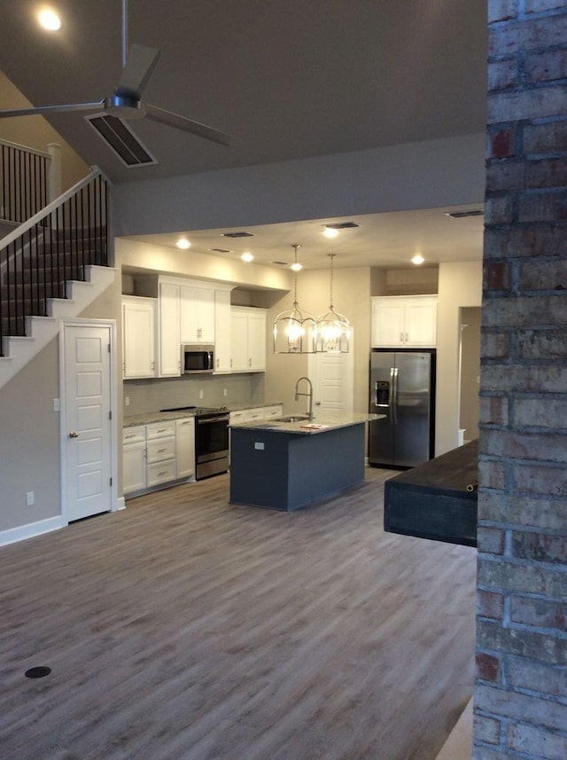 kitchen with hanging light fixtures, an island with sink, appliances with stainless steel finishes, and white cabinets