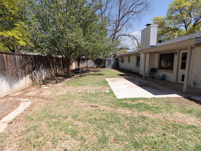 view of yard with a storage unit, a patio area, an outbuilding, and a fenced backyard