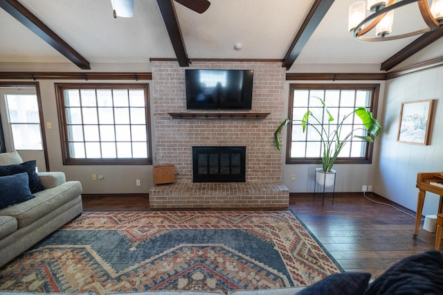 living area featuring beamed ceiling, a fireplace, a ceiling fan, a textured ceiling, and hardwood / wood-style floors