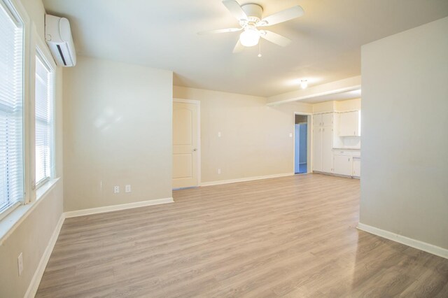 empty room with ceiling fan, a wall mounted AC, and light wood-type flooring