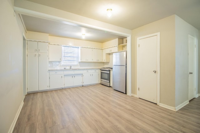 kitchen with sink, white cabinets, decorative backsplash, stainless steel appliances, and light hardwood / wood-style flooring