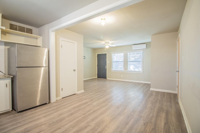 kitchen with ceiling fan, a wall mounted air conditioner, stainless steel fridge, and light hardwood / wood-style floors