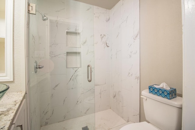 bathroom featuring a shower with door and toilet