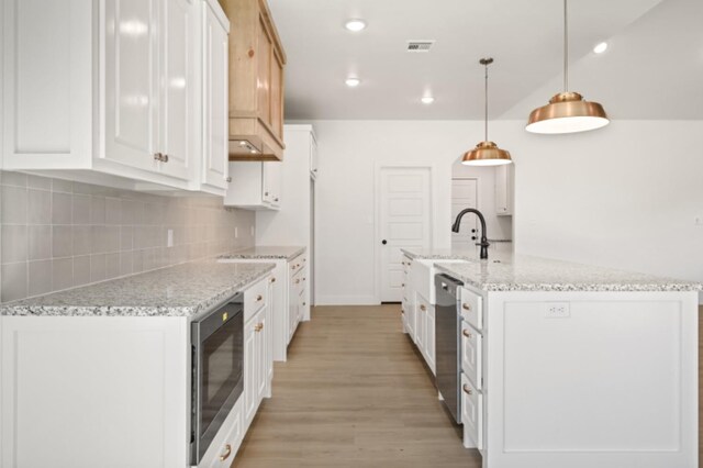 kitchen featuring hanging light fixtures, white cabinets, dishwasher, and a center island with sink