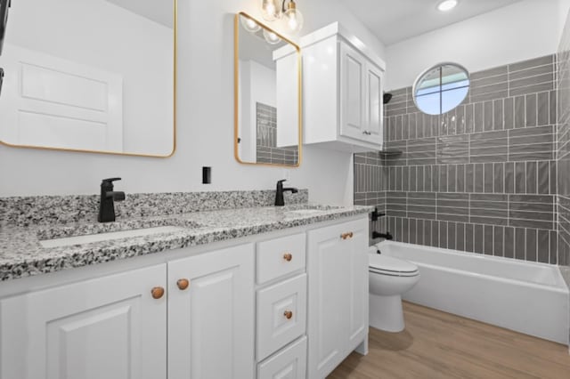 full bathroom with hardwood / wood-style flooring, vanity, toilet, and tiled shower / bath combo