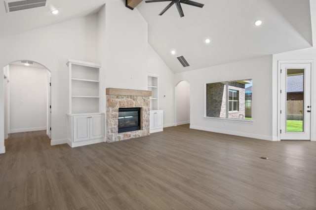 unfurnished living room featuring dark wood-type flooring, high vaulted ceiling, built in features, ceiling fan, and a fireplace