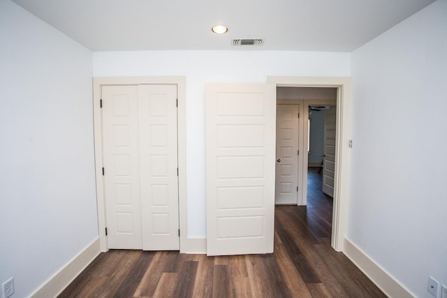 unfurnished bedroom featuring dark hardwood / wood-style flooring and a closet