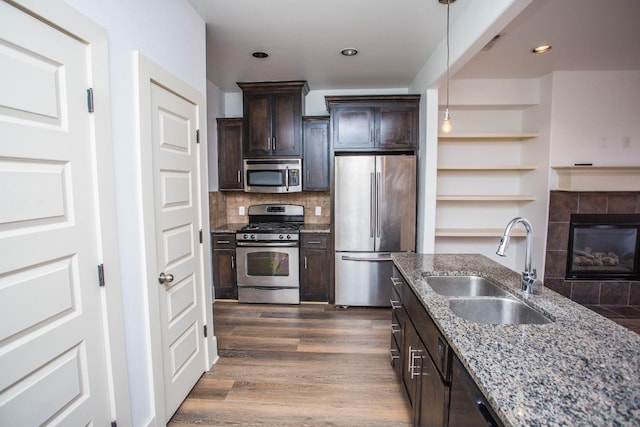 kitchen featuring dark wood-type flooring, dark brown cabinetry, sink, light stone counters, and appliances with stainless steel finishes