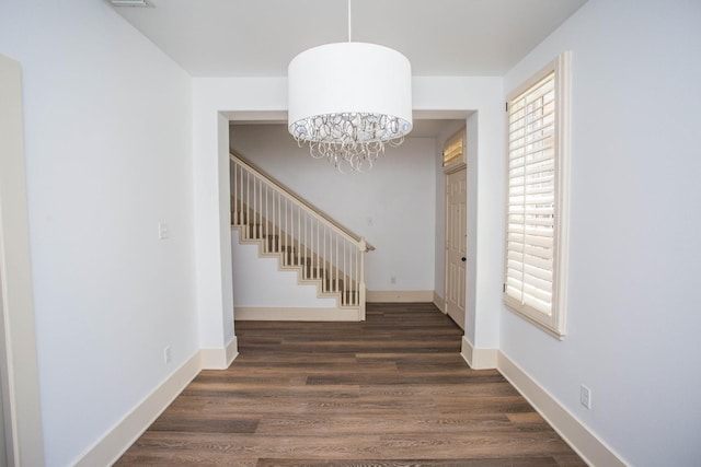 hall with dark wood-type flooring and an inviting chandelier