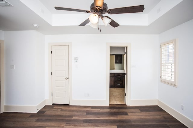 unfurnished bedroom with dark hardwood / wood-style flooring, connected bathroom, and a tray ceiling