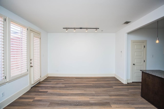 unfurnished dining area featuring track lighting and dark hardwood / wood-style floors