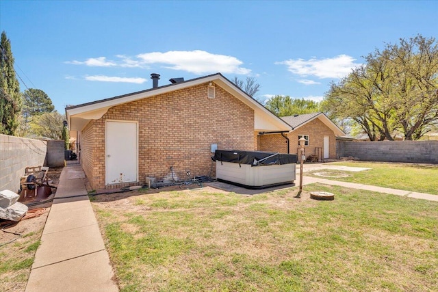 2004 Rice Dr, Levelland, TX 79336 - view of side of property with brick siding, a fenced backyard, a hot tub, and a yard