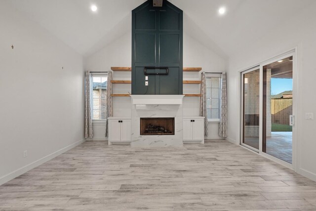 unfurnished living room featuring a fireplace, high vaulted ceiling, light wood-type flooring, and baseboards