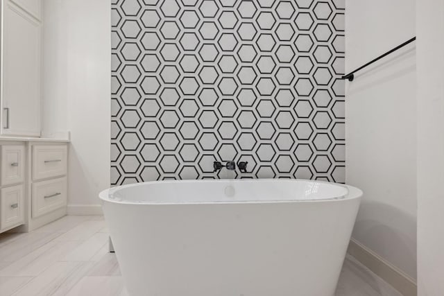 full bathroom with a freestanding tub, baseboards, tile walls, and vanity