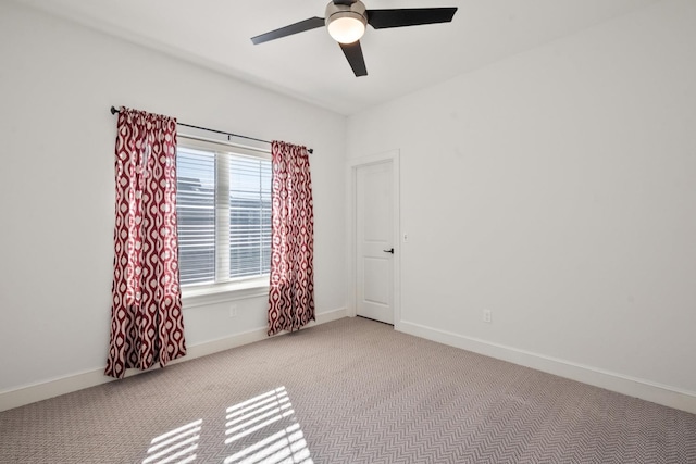 carpeted empty room with baseboards and a ceiling fan