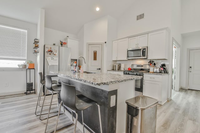 kitchen featuring white cabinetry, stainless steel appliances, sink, and a center island with sink