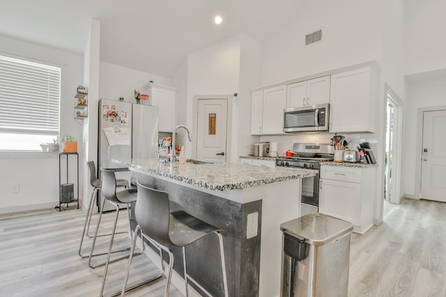 kitchen with sink, an island with sink, white cabinets, and appliances with stainless steel finishes