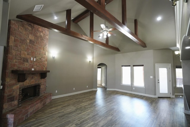 living room with ceiling fan, high vaulted ceiling, dark hardwood / wood-style floors, a stone fireplace, and beamed ceiling