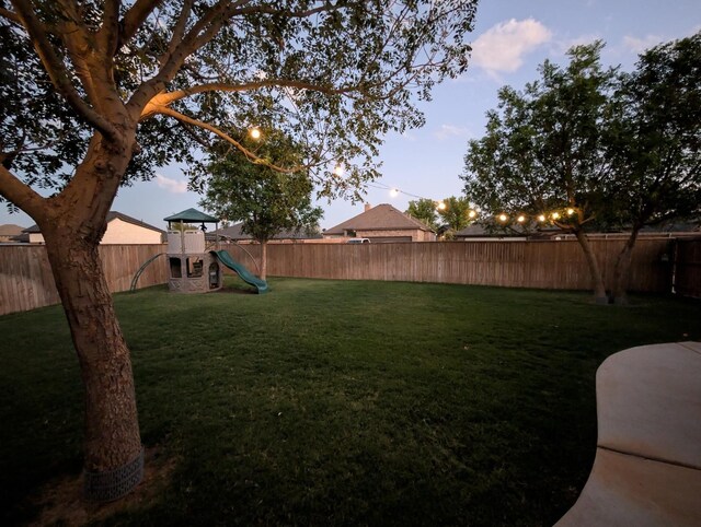 yard at dusk featuring a playground