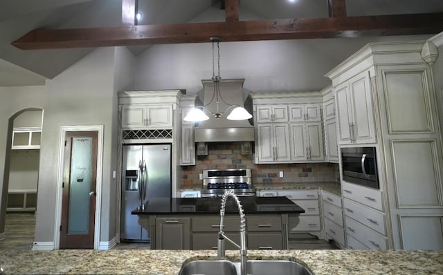 kitchen featuring a kitchen island, appliances with stainless steel finishes, sink, dark stone countertops, and hanging light fixtures