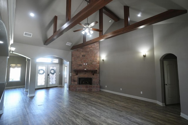 unfurnished living room with french doors, dark hardwood / wood-style flooring, beamed ceiling, ceiling fan, and a fireplace