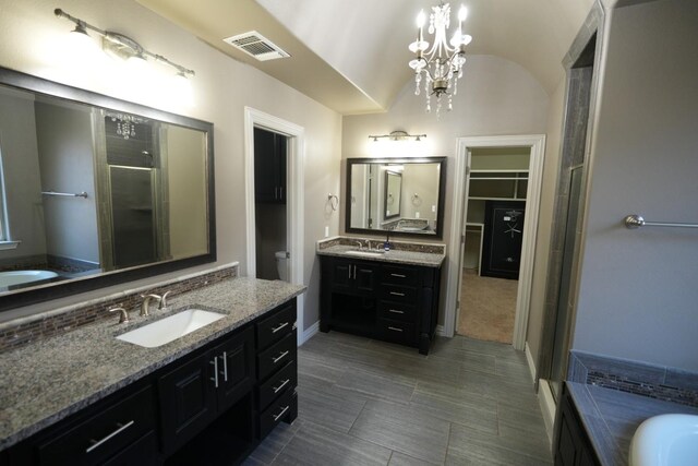 bathroom with an inviting chandelier, vanity, separate shower and tub, and vaulted ceiling