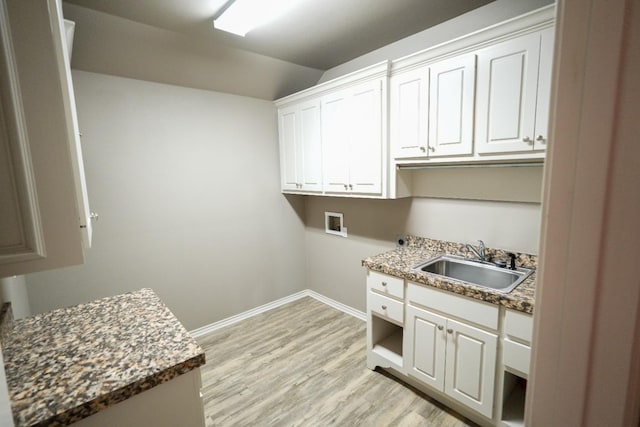 laundry room with sink, hookup for a washing machine, light hardwood / wood-style flooring, and cabinets