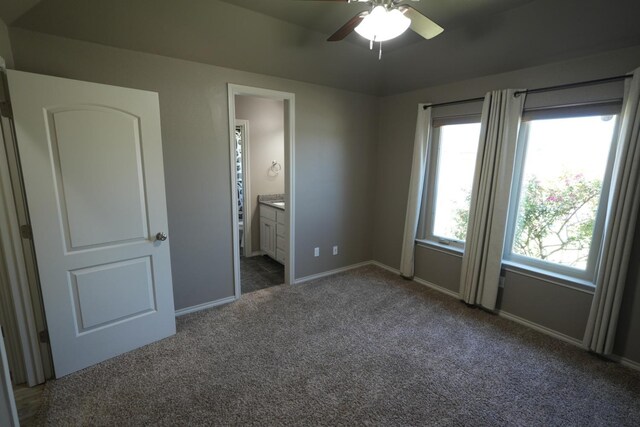 unfurnished bedroom featuring dark colored carpet, connected bathroom, and ceiling fan