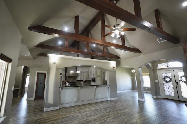 unfurnished living room featuring hardwood / wood-style flooring, ceiling fan, high vaulted ceiling, and beam ceiling