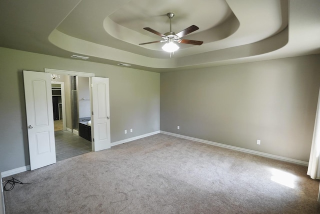 carpeted empty room featuring a tray ceiling and ceiling fan